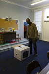 Eric Crawford in Sandy Island School Classroom Standing by a Boxed Printer by The Athenaeum Press