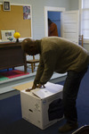 Eric Crawford in Sandy Island School Classroom Opening a Printer Box by The Athenaeum Press