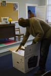 Eric Crawford in Sandy Island School Classroom Opening a Printer Box 2 by The Athenaeum Press
