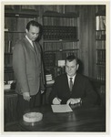Photo of two men in an office signing a document by Lonnie W. Fleming Sr.