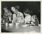 Mother feeding a child at a Conway Kiwanis pancake fundraiser by Lonnie W. Fleming Sr.