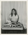A girl working at a table covered with photographs by Lonnie W. Fleming Sr.
