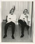 Two men in white suits and black pants sitting in fold up chairs by Lonnie W. Fleming Sr.