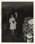 Photo of a bride and groom standing beside their car that is covered in white writing by Lonnie W. Fleming Sr.