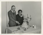 Photo of an elderly couple cutting a cake while looking down at the cake by Lonnie W. Fleming Sr.