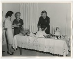 Photo of a woman standing behind a wedding cake wearing a dark colored dress suit by Lonnie W. Fleming Sr.