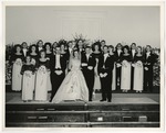 The bride and groom with the wedding party in the background by Lonnie W. Fleming Sr.