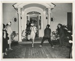The bride and groom are exiting the groom's parents' home while getting rice thrown at them by Lonnie W. Fleming Sr.