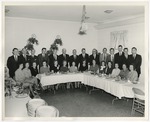 Photo of women seated at a table while men stand behind them by Lonnie W. Fleming Sr.