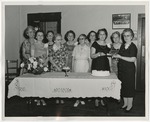 Photo of a group of ten women behind a table with a white tablecloth on it by Lonnie W. Fleming Sr.