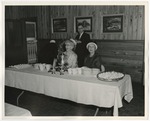 Photo of two elderly women sitting at a reception table and a man in the background by Lonnie W. Fleming Sr.