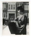 A posed photo of a girl in graduation robes accepting her diploma in front of Conway High School by Lonnie W. Fleming Sr.