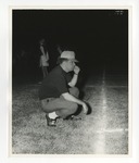 A photo of a man kneeling in the grass with his hand on his mouth watching a game on the field by Lonnie W. Fleming Sr.