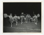 A Photo of a group of cheerleaders running in front of football players and pulling two little girls along with them by Lonnie W. Fleming Sr.