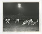 A photo of a football game with a football player about to throw the football on the left side of the Photo by Lonnie W. Fleming Sr.