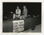 A photo of two young ladies sitting on top of a car; a young man can be seen driving the car by Lonnie W. Fleming Sr.