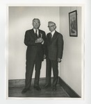 Two suited gentlemen jointly holding a single cup by Lonnie W. Fleming Sr.