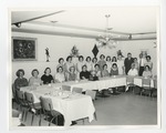 A group of adults sitting and standing at a U-shaped table with white cloth by Lonnie W. Fleming Sr.