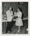A male and female holding a large award and shaking hands by Lonnie W. Fleming Sr.