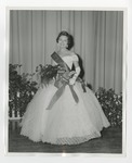 A woman in a dress wearing a crown, sash, ribbon, and bouquet by Lonnie W. Fleming Sr.