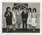 A photo of a group of dressed students posing in front of the "Distributive Education Clubs of America" banner by Lonnie W. Fleming Sr.