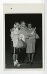 A man in a coat hugging a cheerleader and an older woman whom are both wearing warm clothing by Lonnie W. Fleming Sr.