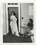 A woman wearing robes and walking into a classroom by Lonnie W. Fleming Sr.