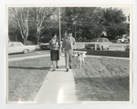 A man, woman, and dog walking down a sidewalk by Lonnie W. Fleming Sr.