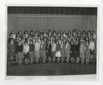 A large group of young women taking a group photo in front of a curtain by Lonnie W. Fleming Sr.