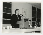 A suited gentleman speaking at a podium by Lonnie W. Fleming Sr.