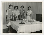 Four women standing behind a serving table by Lonnie W. Fleming Sr.